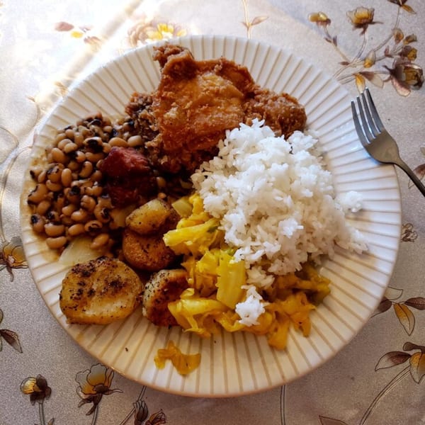 A Salsabor Restaurant plate with fried chicken, rice, black-eyed peas, fried plantains, and yellow cabbage.