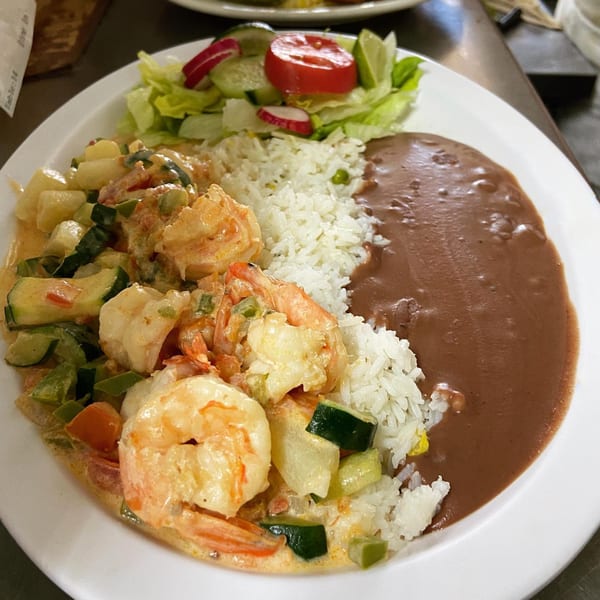 Salsabor Restaurant's shrimp in cream sauce with rice, refried beans, and a side salad.