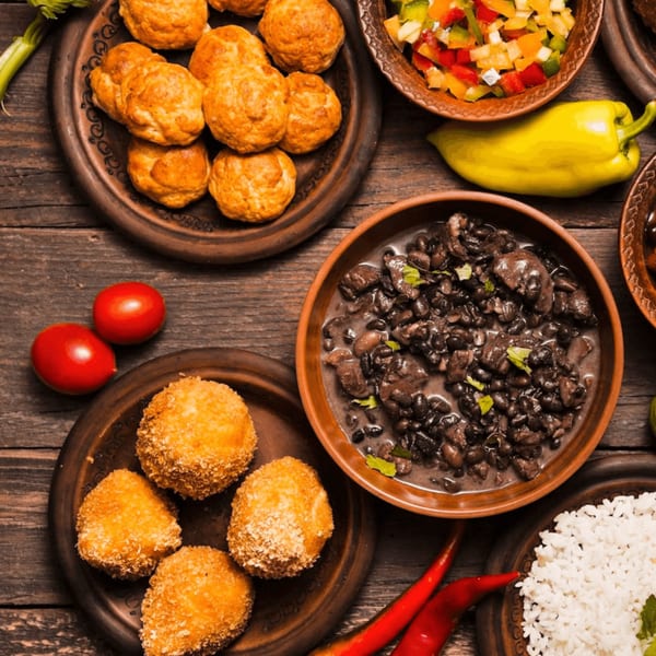 A top-down view of various Salvadoran dishes, including black beans, rice, fried plantains, and pupusas.